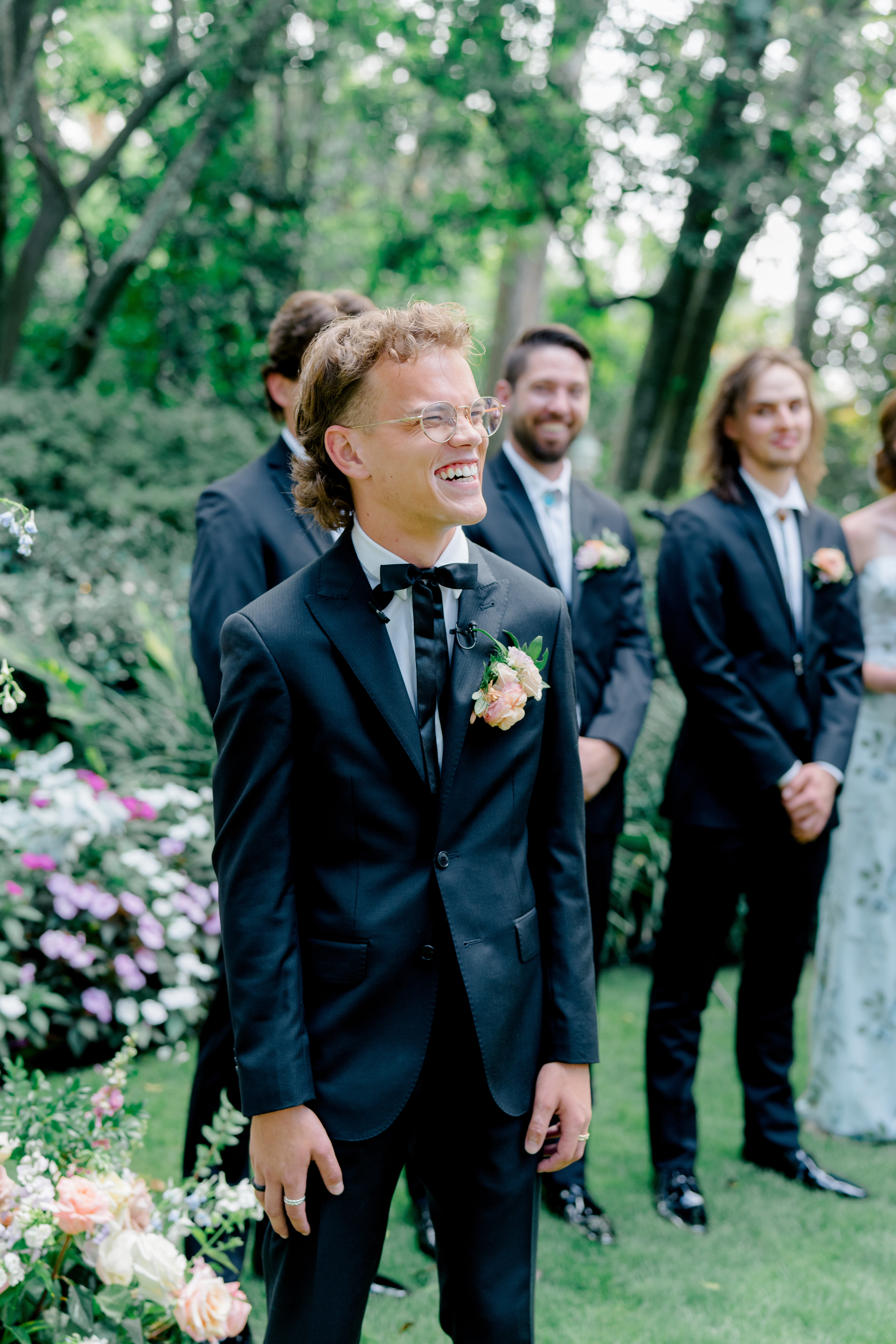 Groom turns around at wedding ceremony to see bride for the first time on wedding day. Groom in unique tie and pocket square of flowers. 