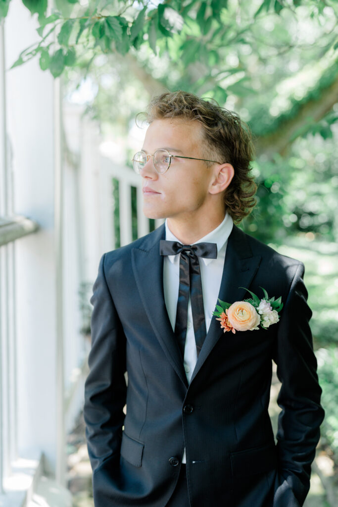 Groom with unique bow tie, classy mullet, and pocket square of live flowers. 