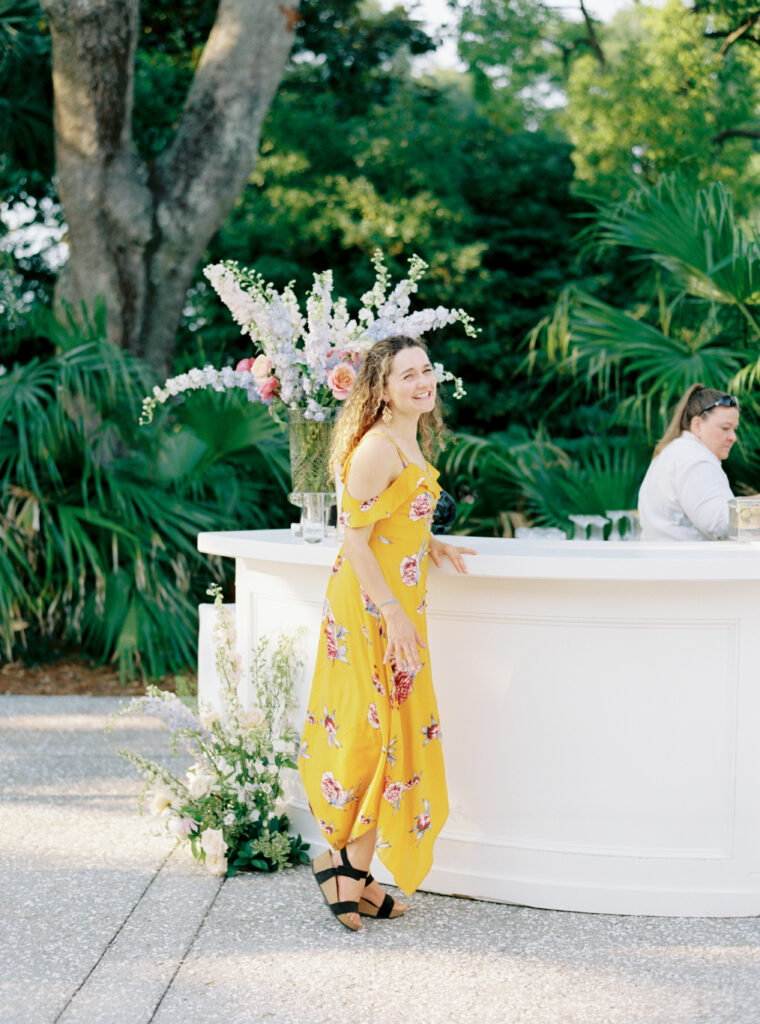 Wedding guest style. Girl in yellow dress waiting for a drink at the bar. 