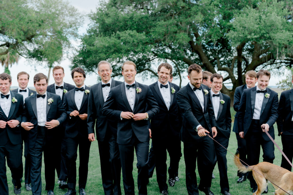 Groom walking with groomsmen and dogs. 