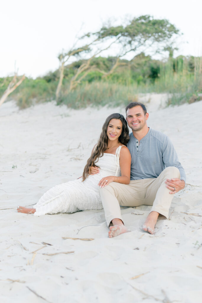 Golden hour beach maternity session. Girl wearing white dress and guy in khakis with casual grey top.