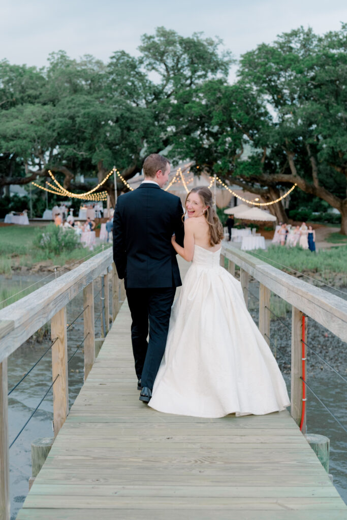 Bride and groom walking away with bride laughing back at camera. 