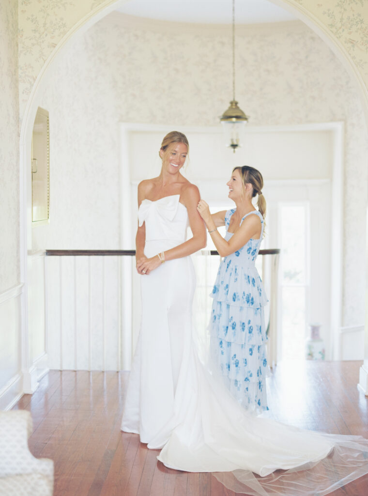 Maid of honor helps bride put in her veil. 