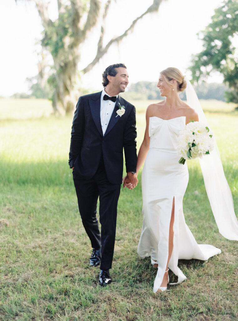 Bride and groom walk together and hold hands. 