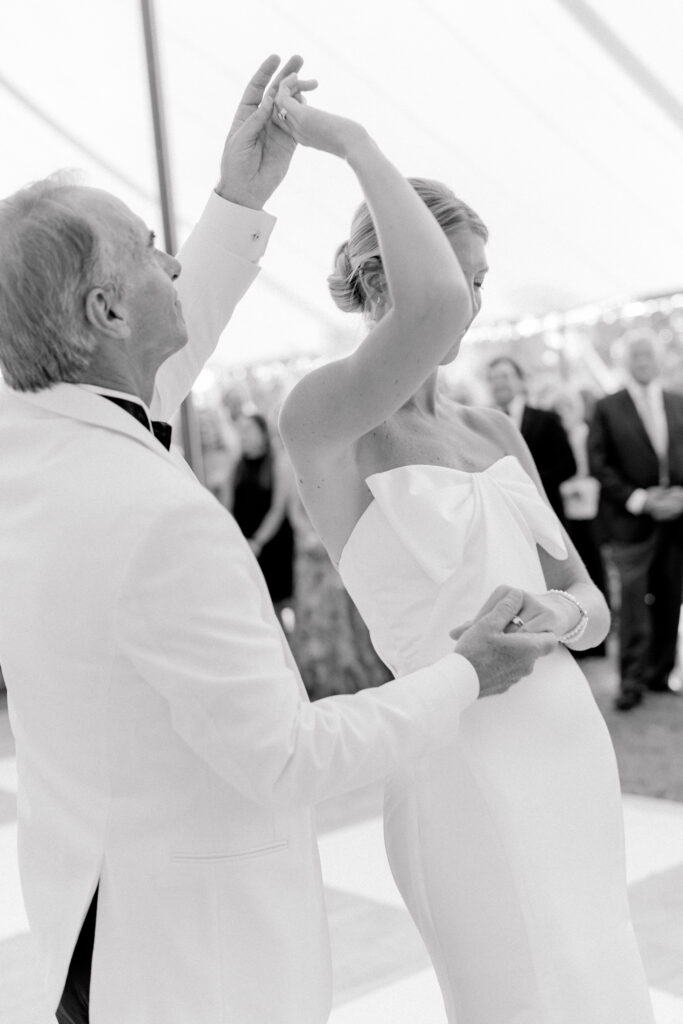 Father of the bride twirls daughter on dance floor during the father daughter dance. Black and white wedding photos.