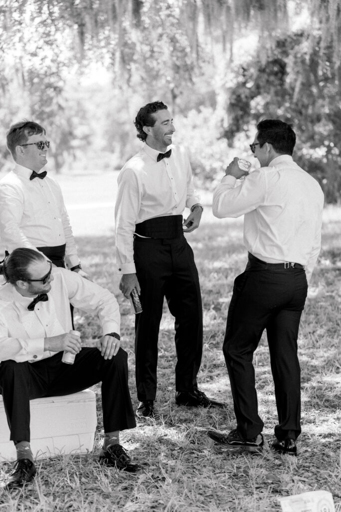 Groom hanging out with groomsmen with spanish moss. One groomsmen sitting on cooler. Destination weddings. 