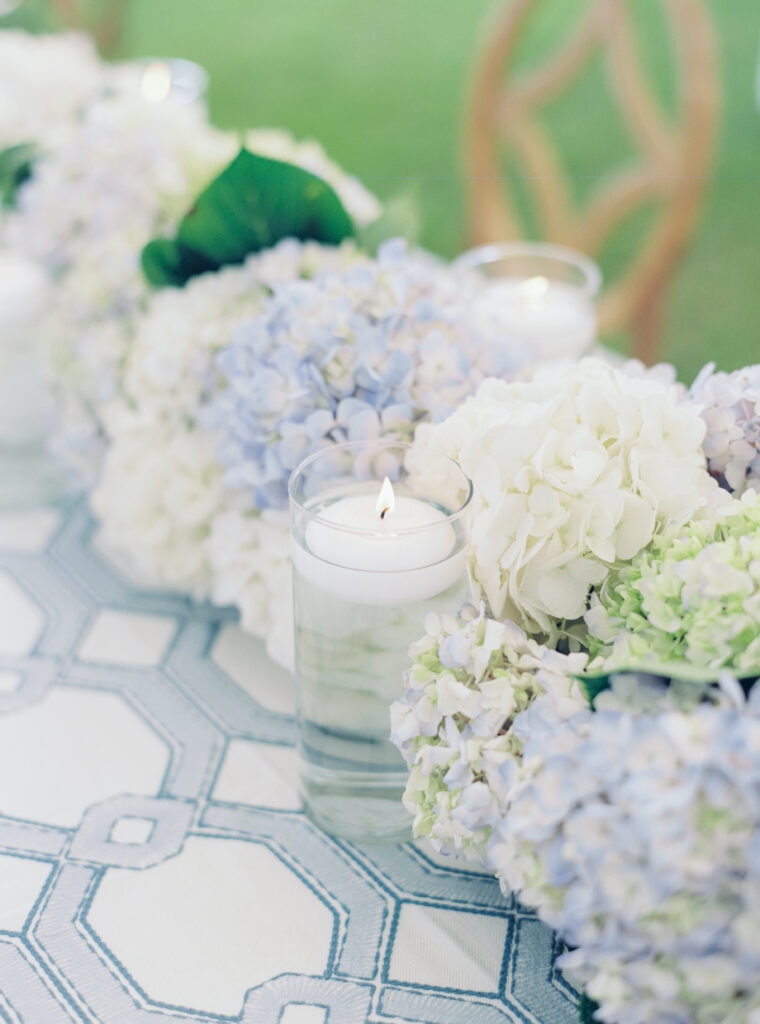 Simple flowers and candle with blue and white patterned table linens. 