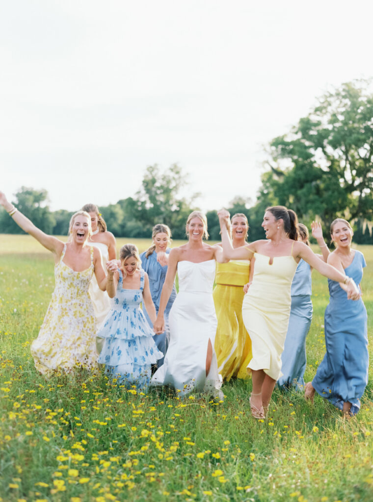 Bride and bridesmaids frolic in the field of yellow wild flowers. 