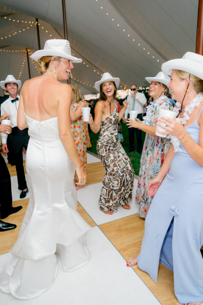 Bride puts on her party hat and dances with wedding guests.