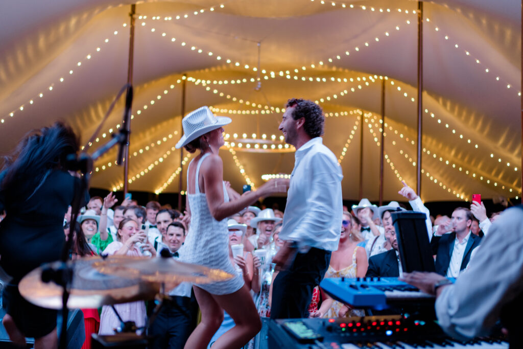 Bride and groom on stage with string lights. 