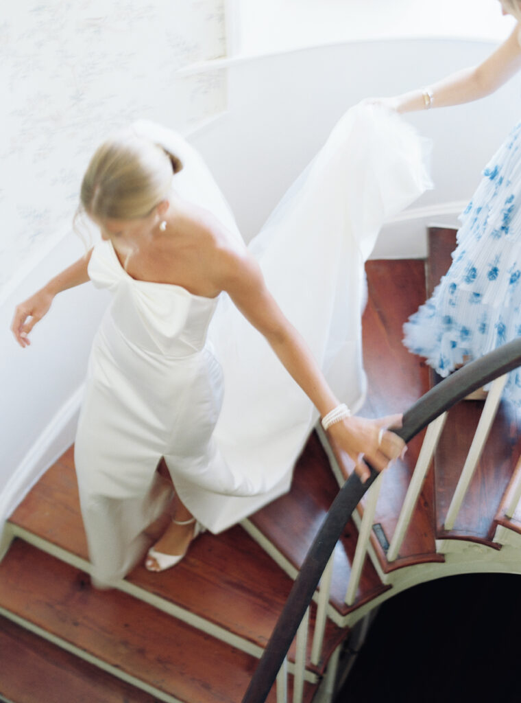 Bride walking down curved staircase in the house at Agapae Oaks. 