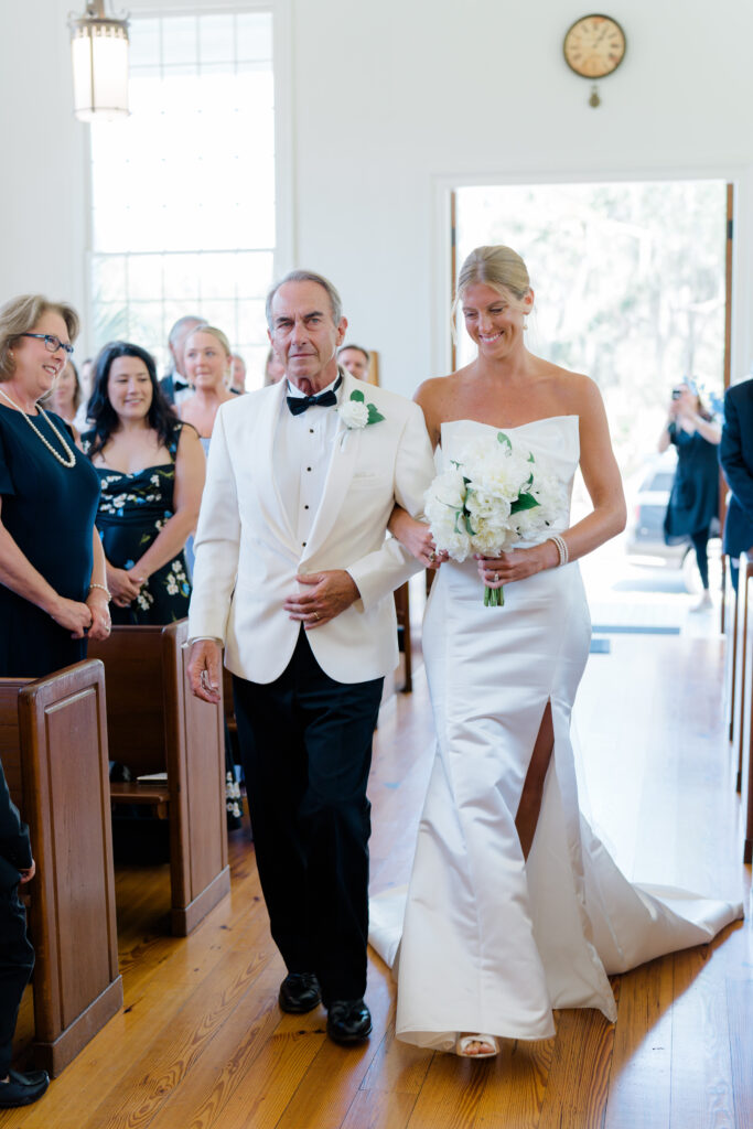 Bride escorted by her dad up the aisle at wedding ceremony. 