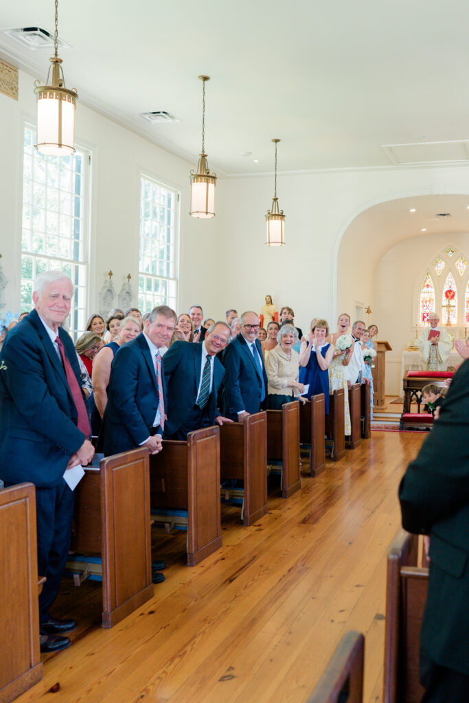 Wedding guests watch from the pews as bride and groom kiss outside of the church. 