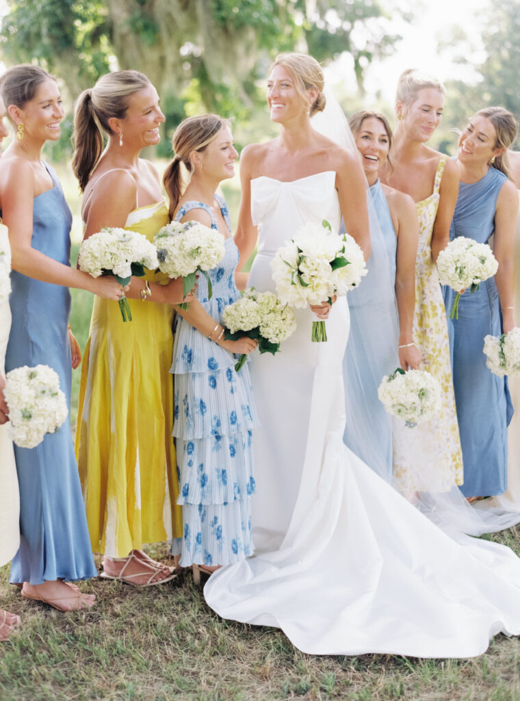 Yellow and blue bridesmaids dresses. Bride smiling with bridal party. 