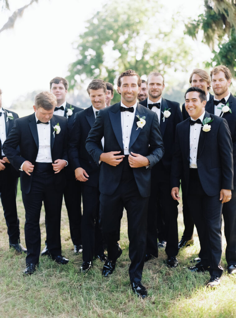 Groom and groomsmen walking and buttoning jackets. 