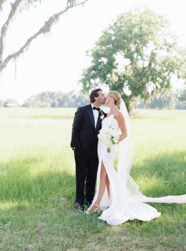 Bride and groom kiss in the field at Agapae Oaks. 