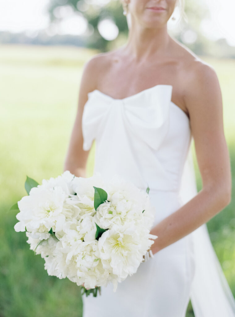 Bride in dress with bow on the chest with simple white flowers. 