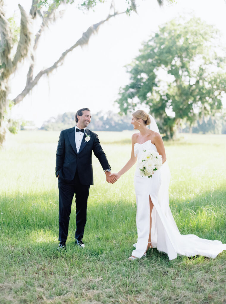 Bride and groom hold hands and look at each other. 