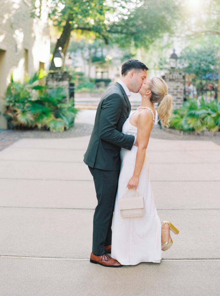 Bride and groom kiss during sunset portraits at Charleston rehearsal dinner.