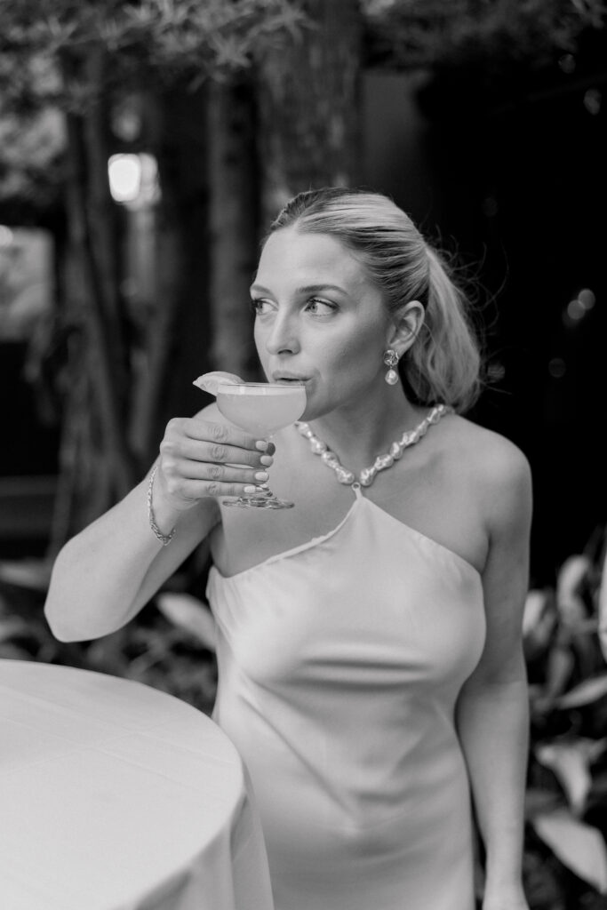 Bride sips a cocktail during rehearsal dinner at High Cotton.