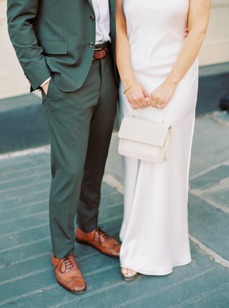 Bride and groom outfits for wedding rehearsal dinner. Groom in dark green suit. 