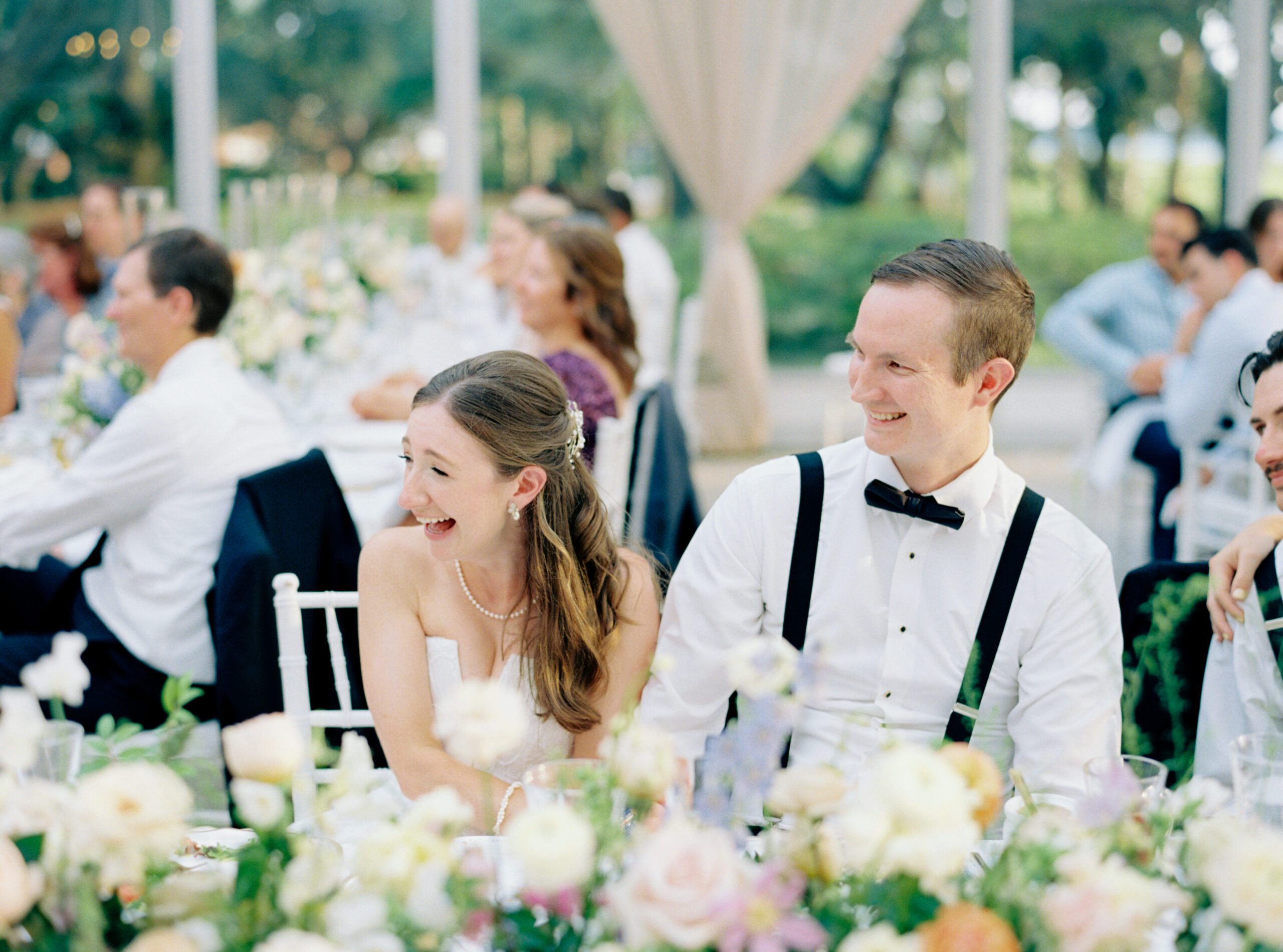 Bride and groom sitting at head table laughing at speeches. Charleston wedding film photographer. 