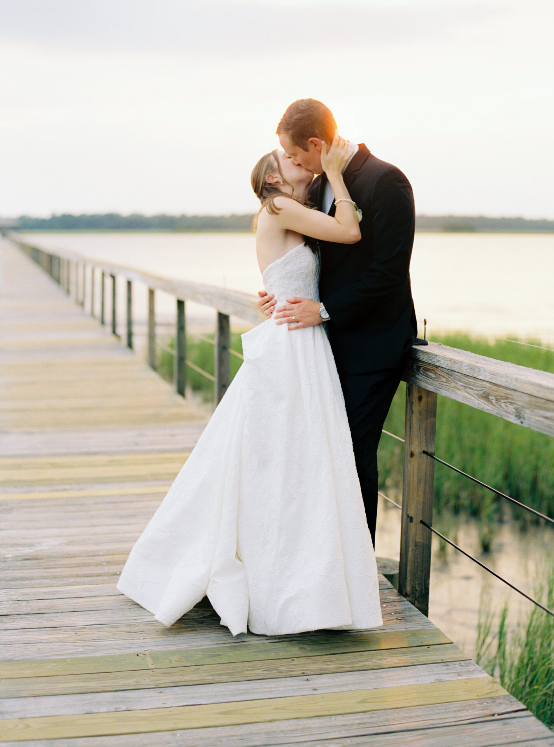 Sunset film photos of the bride and groom on the dock.