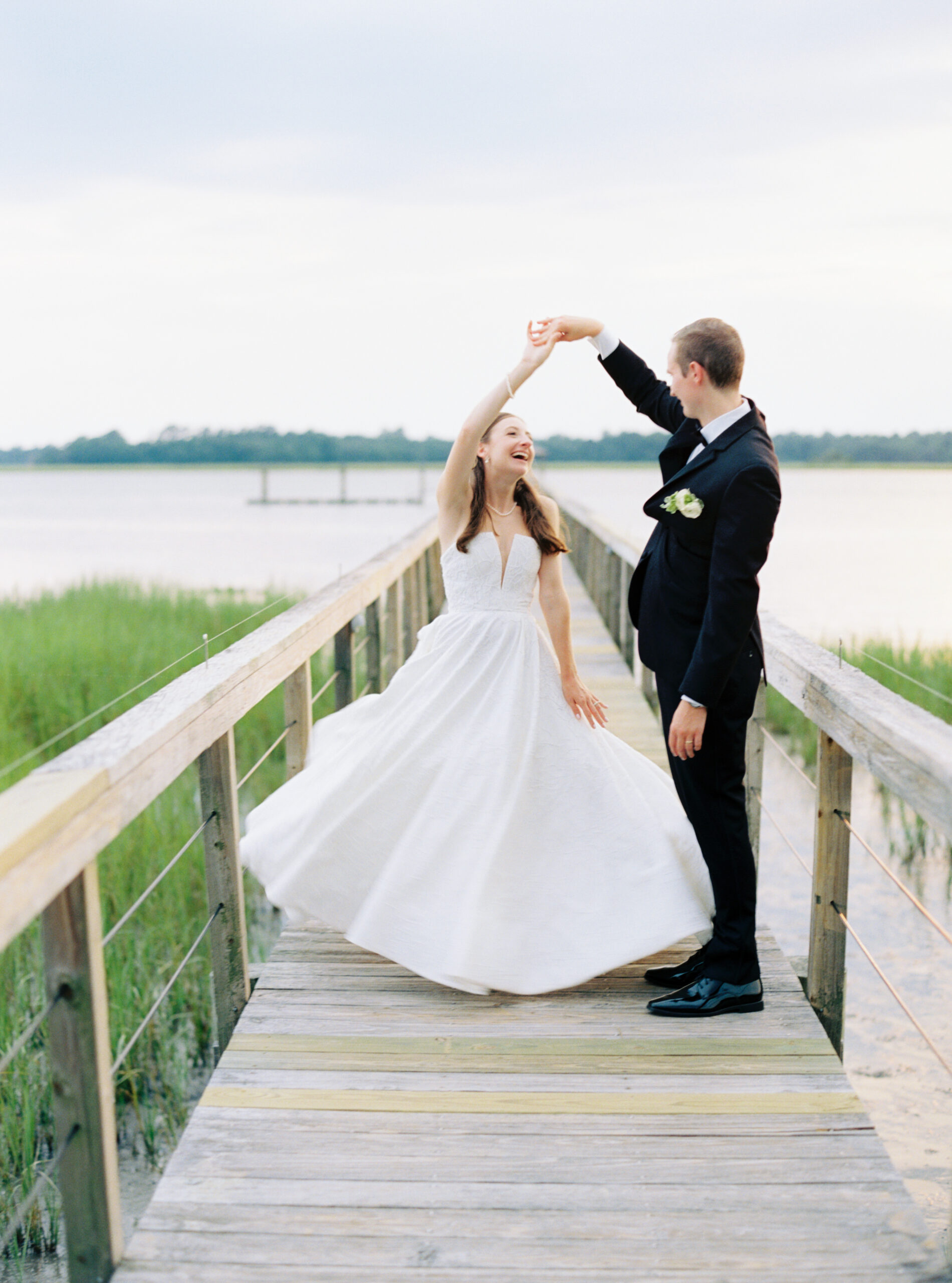 Groom spinning bride around on the dock at Lowndes Grove. Golden sunshine. 