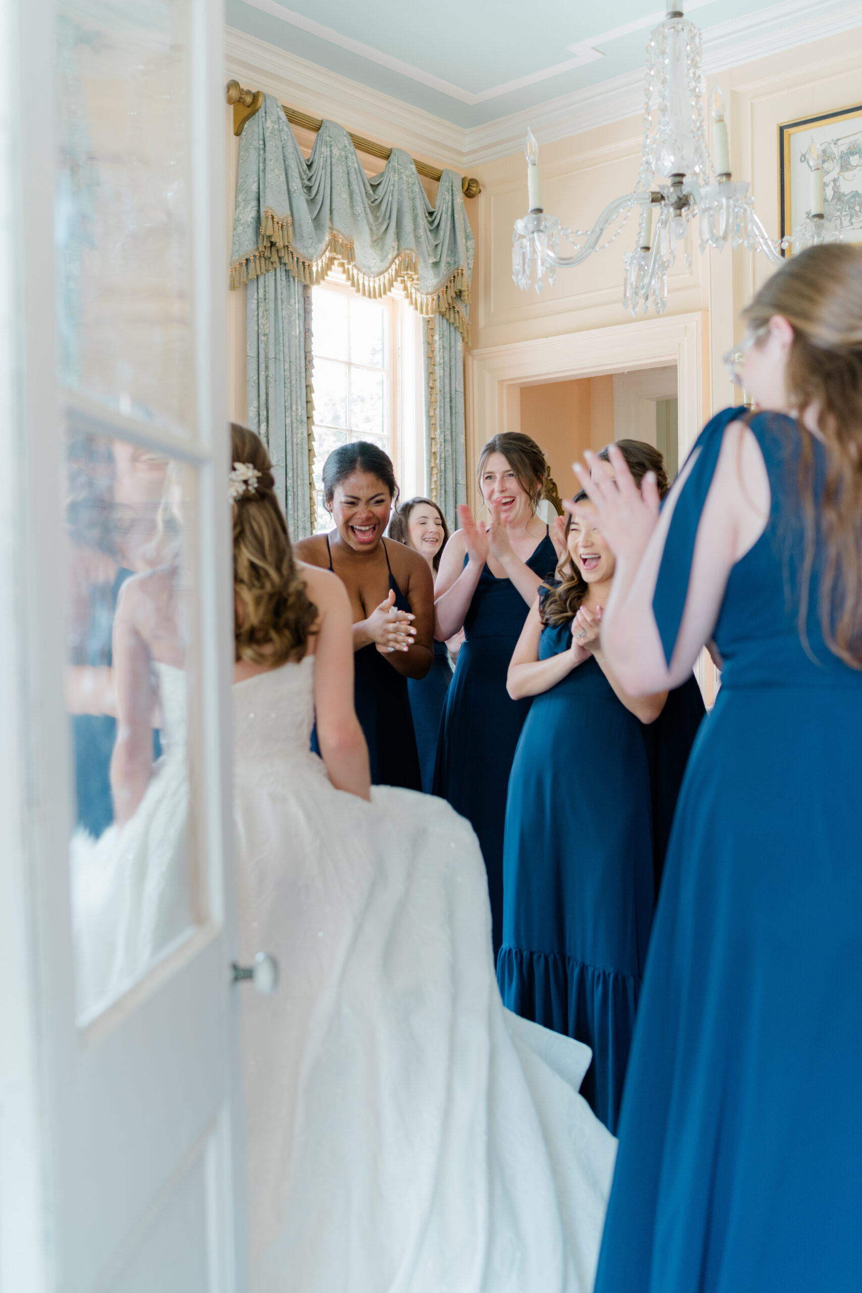 Bridesmaids react to seeing the bride in her wedding dress for the first time. 