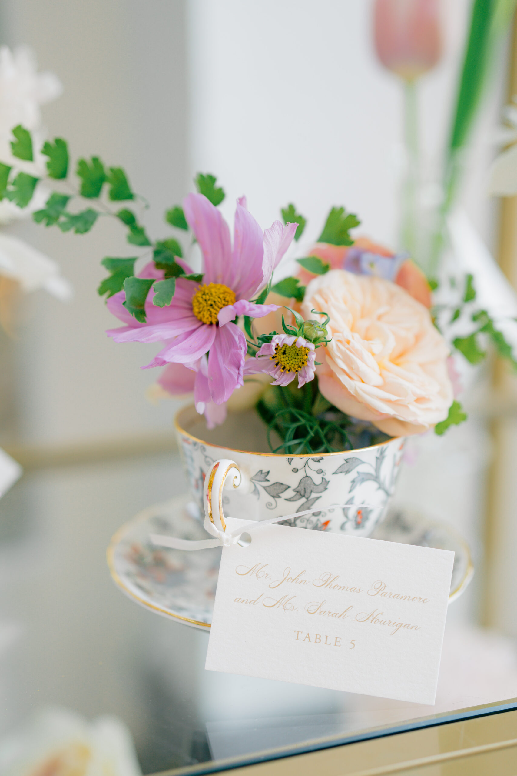 Peach and purple flowers decorating heirloom tea cup seating chart. 