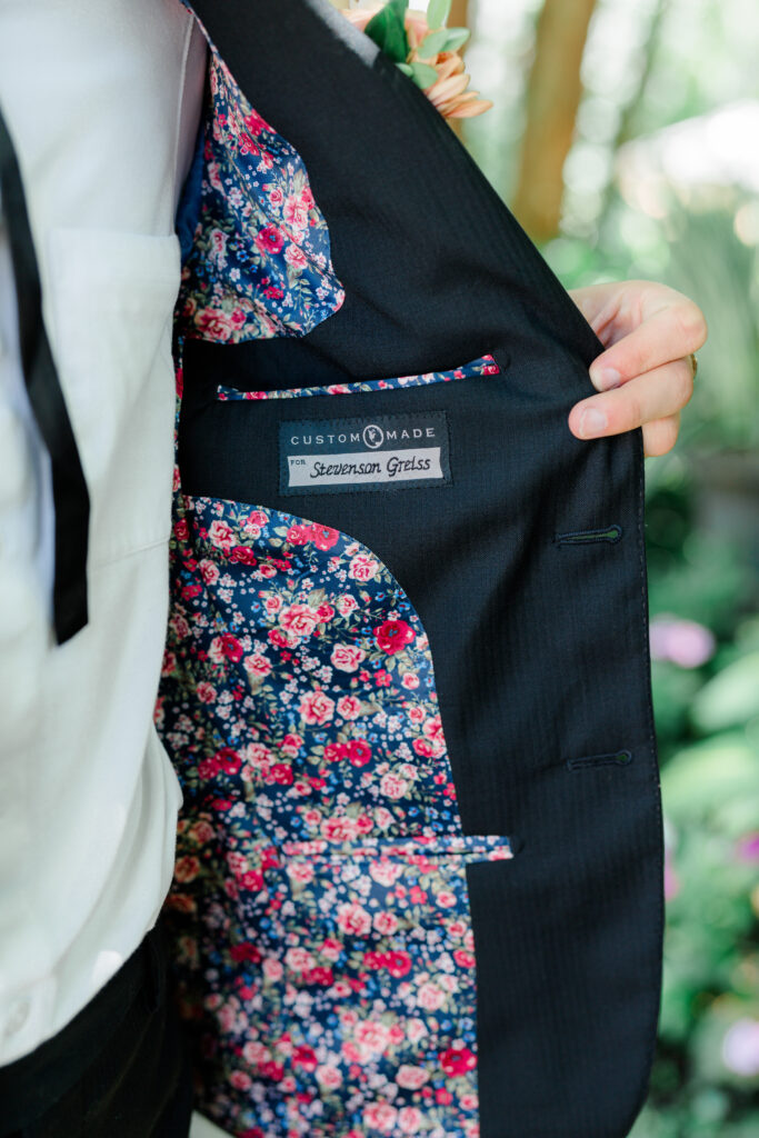 Groom's tuxedo liner has pink flowers inside. 