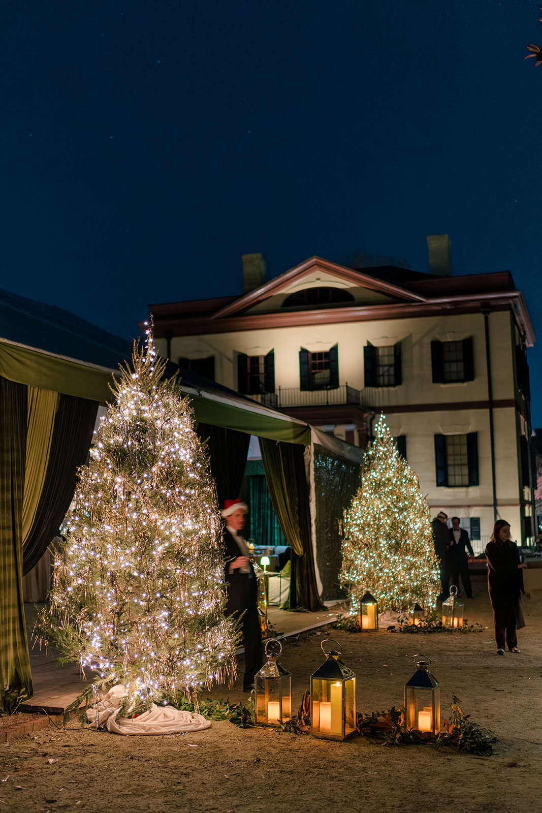 Tinsel covered christmas trees at opening of tent with Hampton Preston Mansion in background.