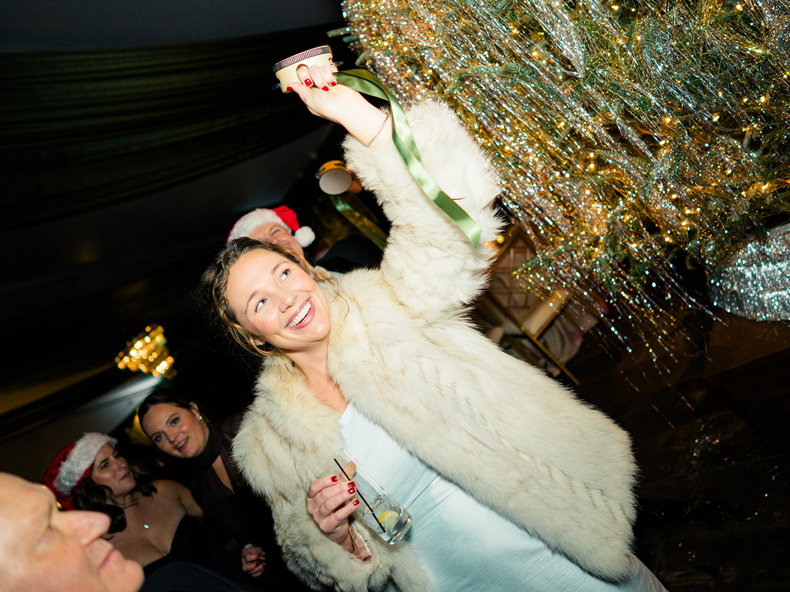 Wedding guests in fur jacket celebrates with mini tambourine with green ribbon.