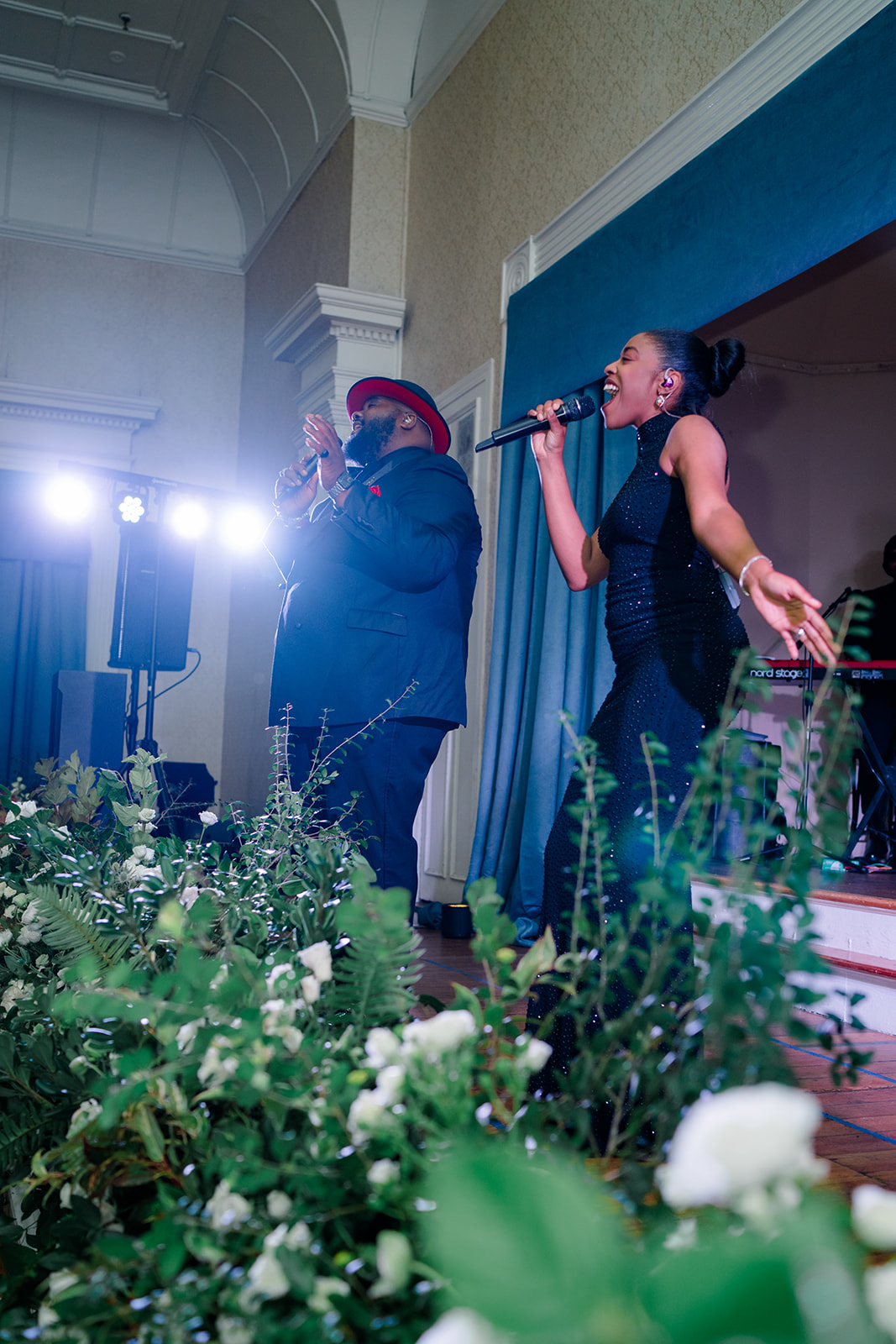 Live band singing with greenery in foreground. 