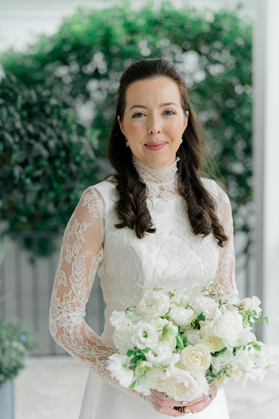 Close up bridal portrait. White and green flowers. Lace sleeves. 