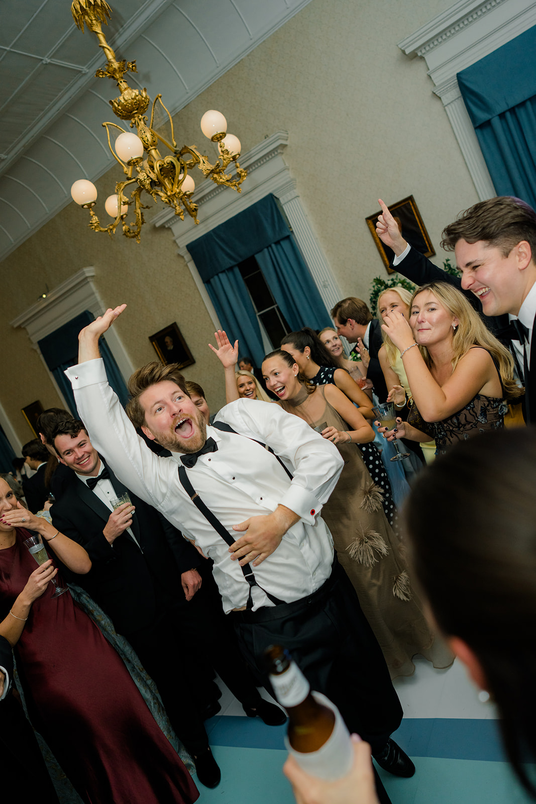 Wedding guest dancing in crowd during reception. 