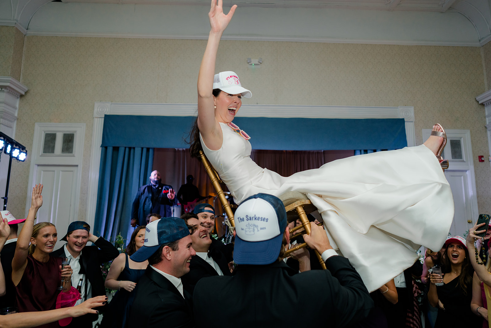 Bride lifted in chair by wedding guests 