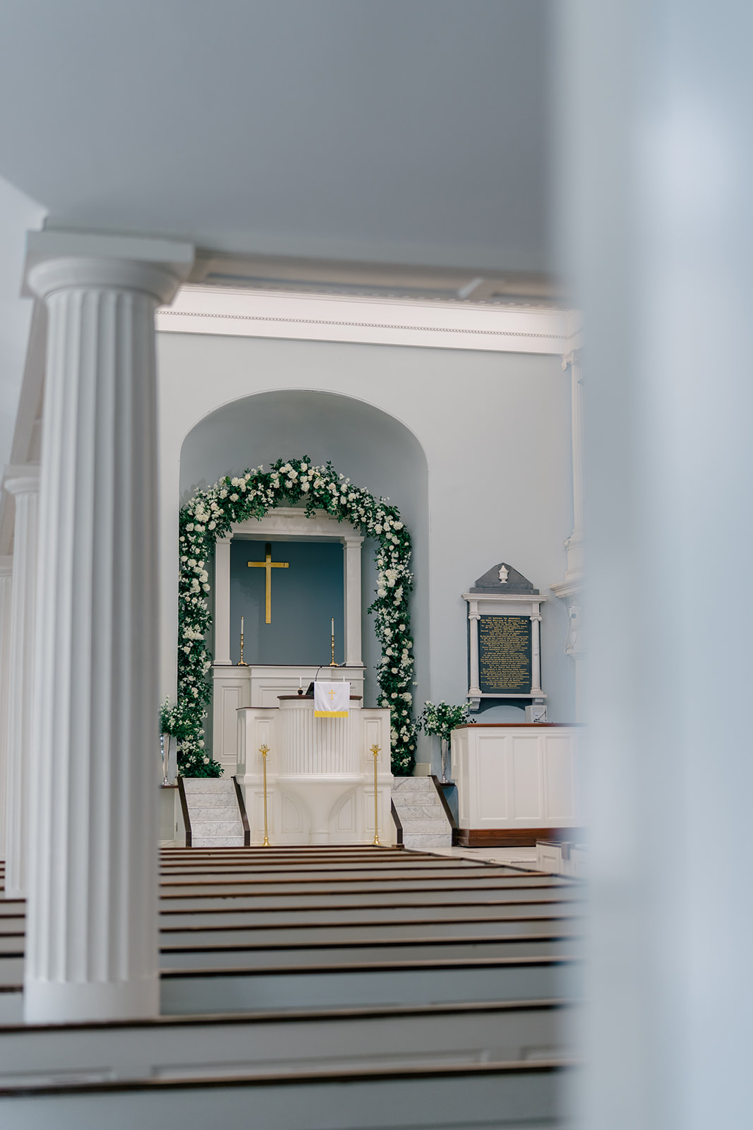 Big floral arch in church. Columns in foreground. Downtown Charleston Church ceremony. 
