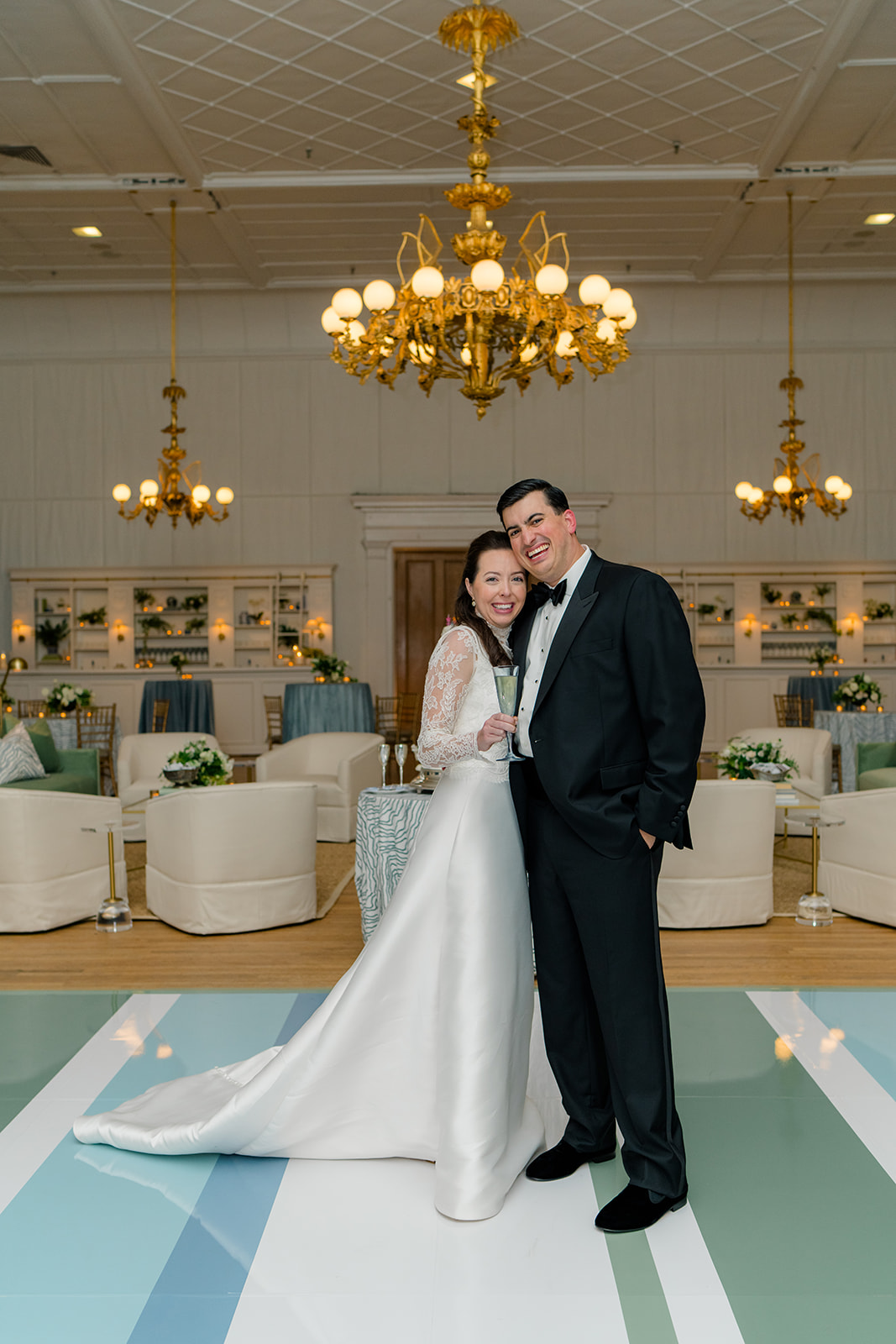 bride and groom stop for a picture on custom dance floor. blue, green, and white pattern. 
