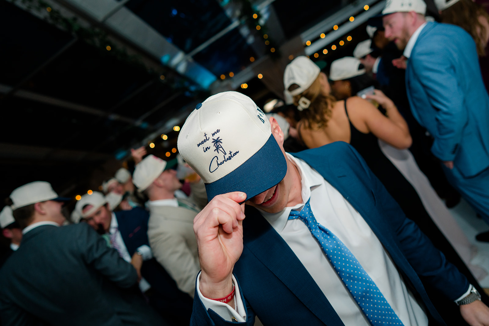 wedding guest shows off "meet me in charleston" wedding baseball hat. Lowndes Grove winter wedding. 
