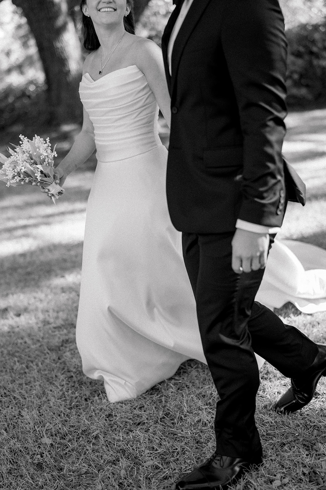 Bride and groom holding hands, walking together, and looking at each other. 