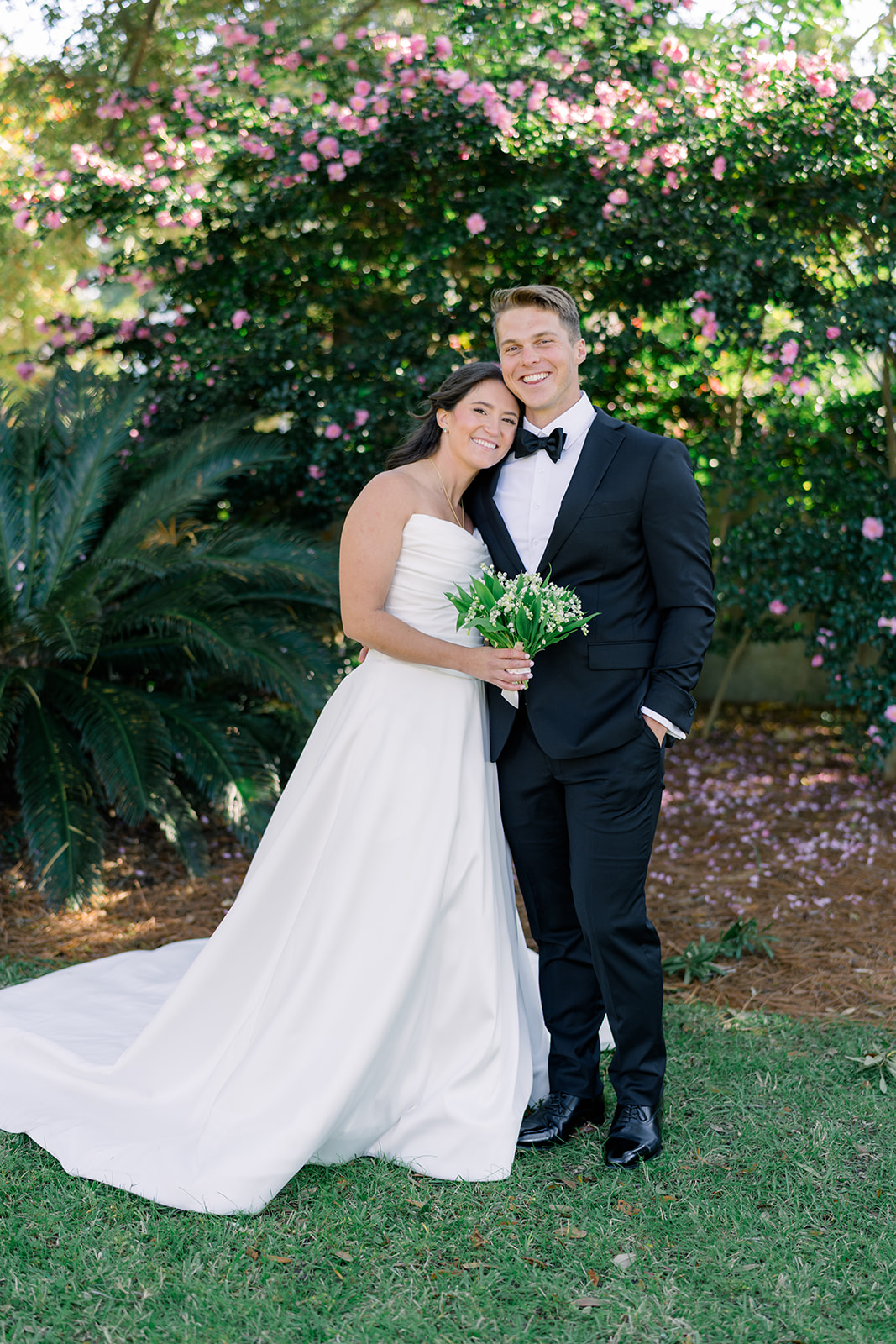 Bride and groom standing in front of pink flowers for a portrait. Charleston Winter Destination Wedding. 