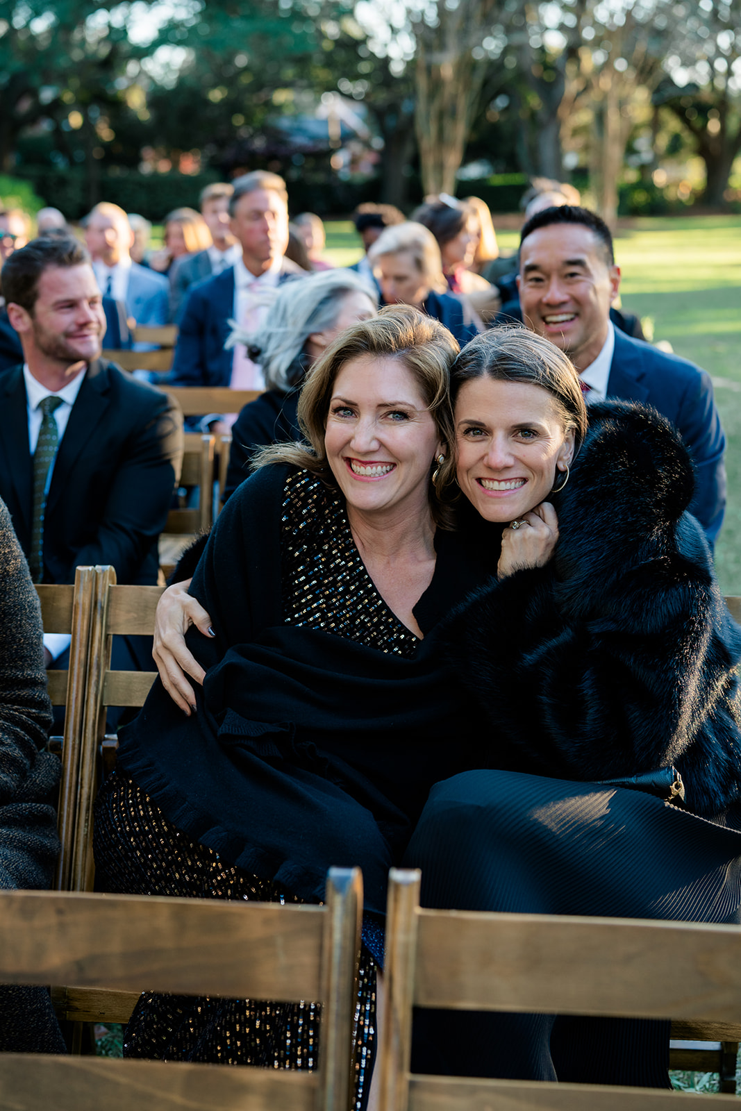 Wedding guests huddle together for warmth during outdoor winter wedding ceremony on the front lawn at Lowndes Grove. 
