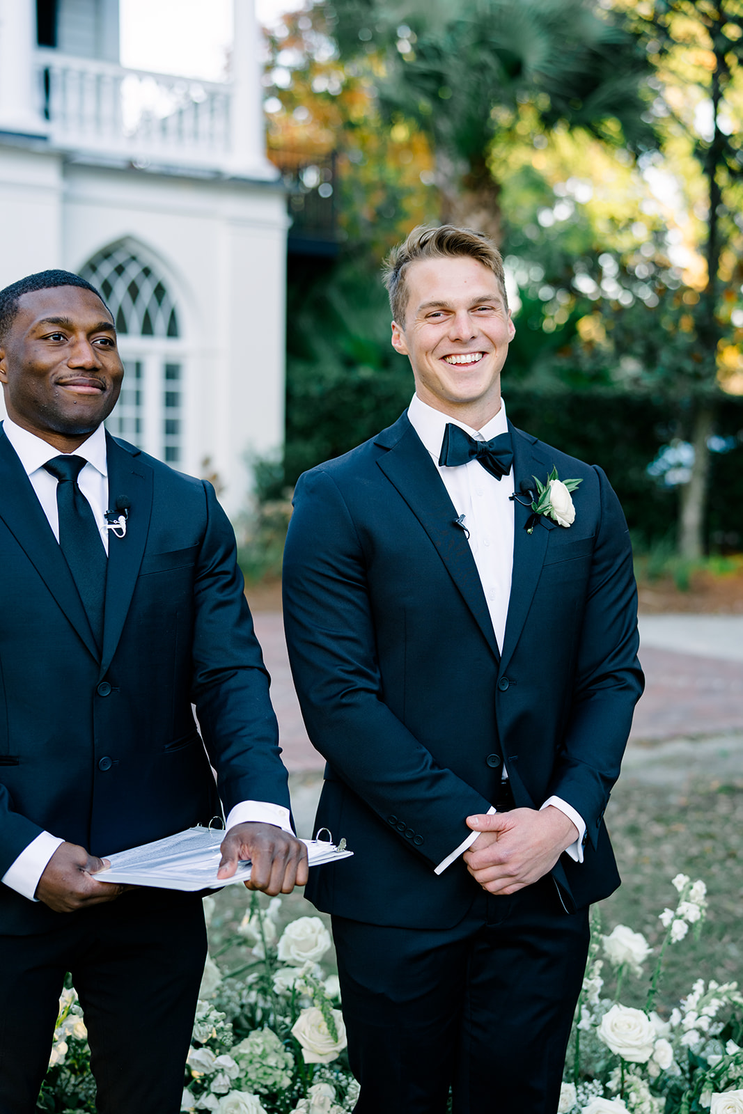 Groom smiles at the camera with officiant smiling too.