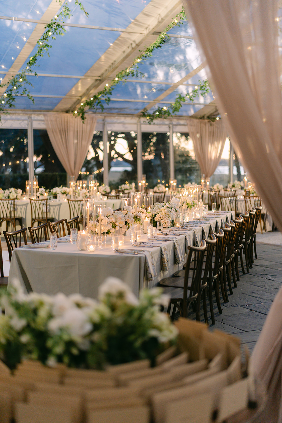 Candlelight dinner at Lowndes Grove winter wedding reception. Greenery and string lights with draping. 