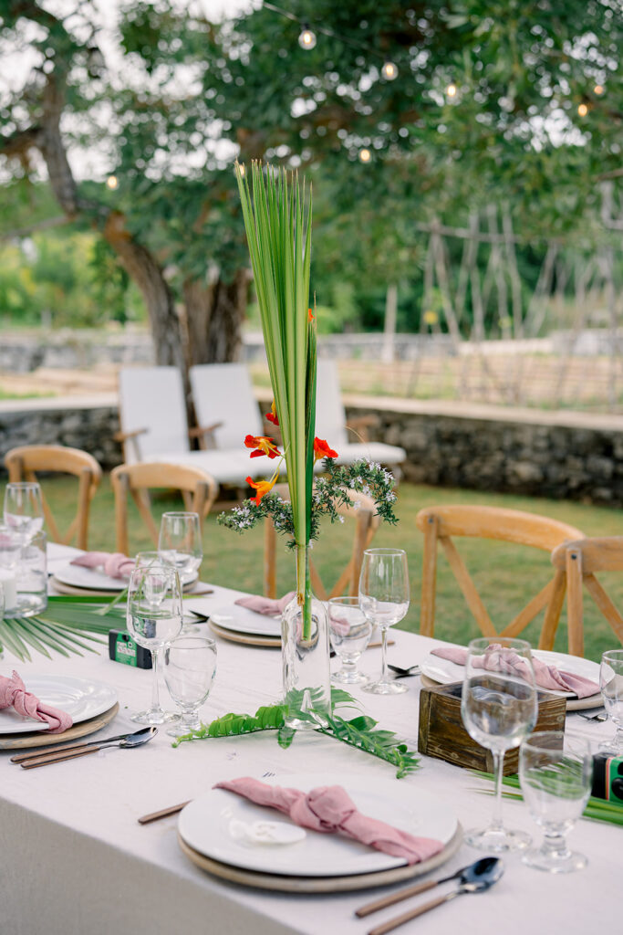 Palm greenery and flowers with pink linen napkins.