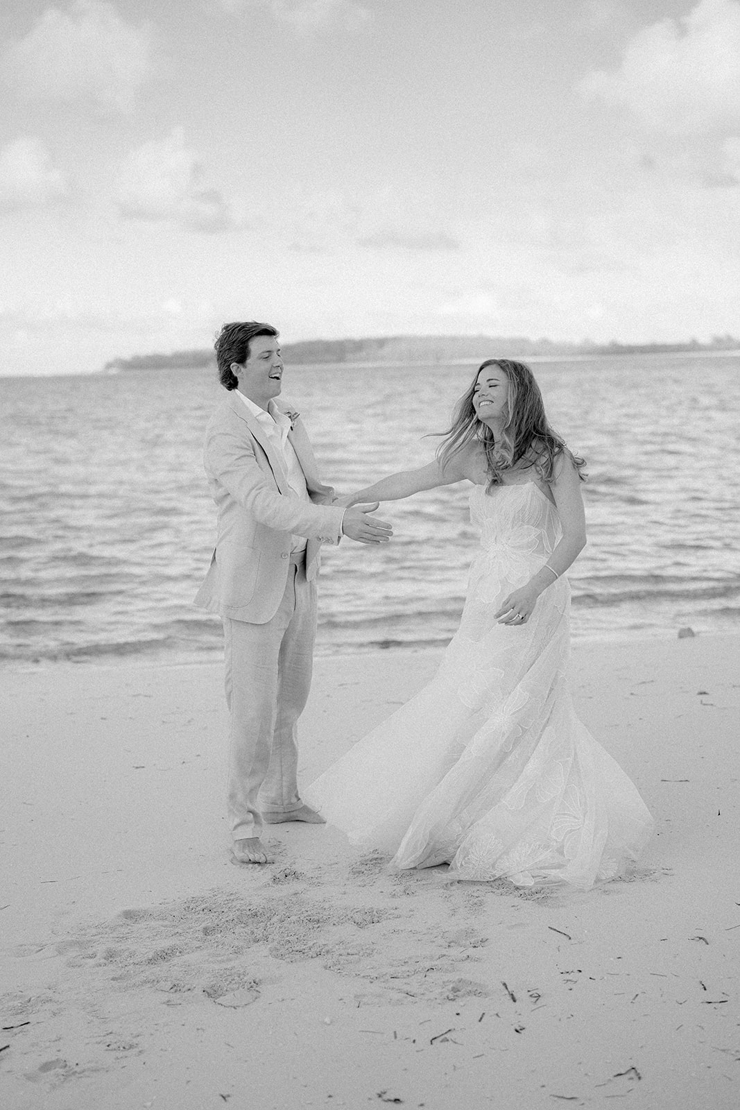 Black and white photo of bride and groom dancing on the beach. 