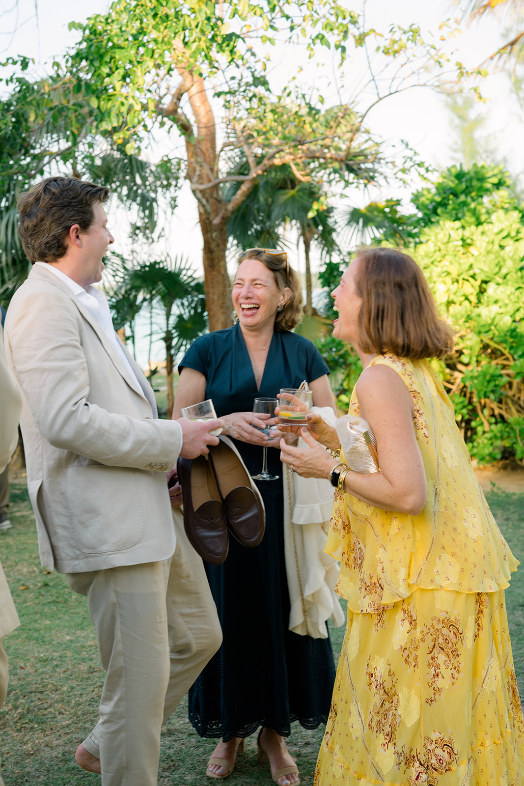 Groom laughs with wedding guests at cocktail hour. 