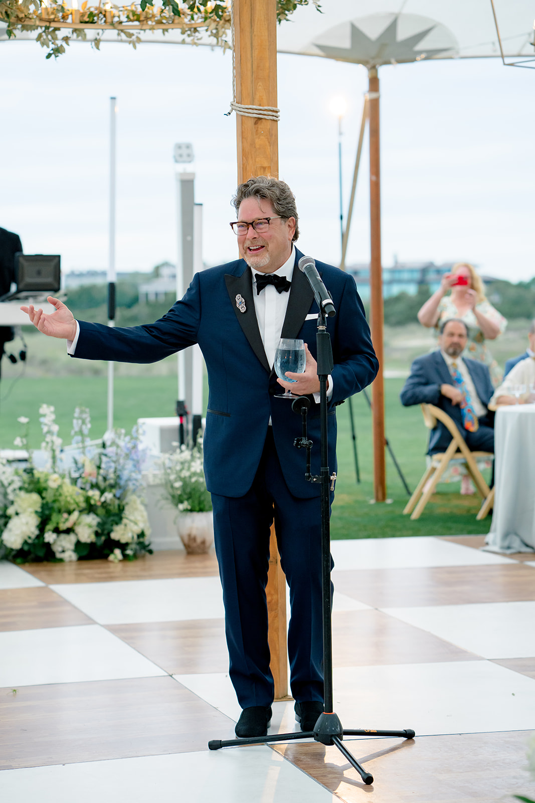 Father of the bride in navy tuxedo welcome toast. 