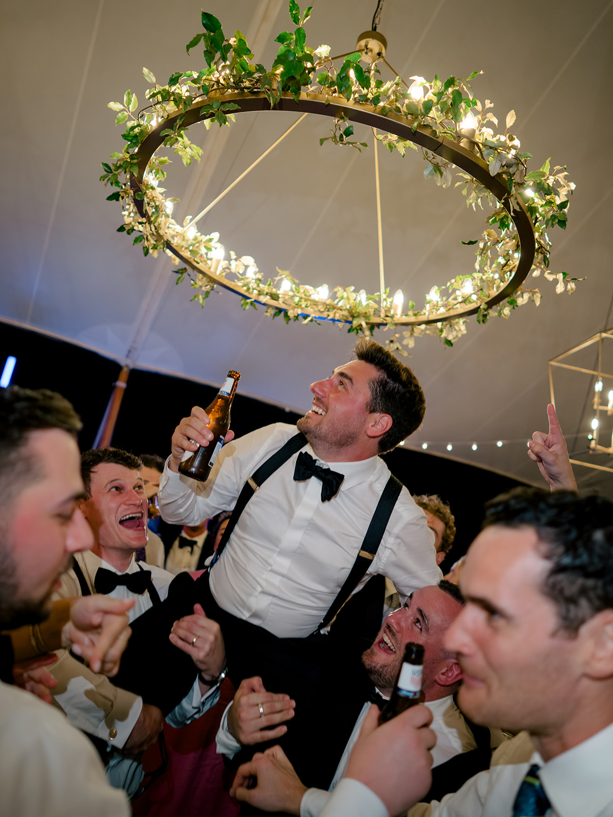 Groom lifted up by friends on the dance floor at ocean course reception. 